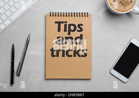 Notizbuch mit Text Tipps und Tricks auf hellgrauem Tisch, flach liegend Stockfoto