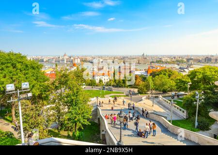 Touristen gehen die lange Treppe vom Budaer Schlosskomplex, mit dem Parlamentsgebäude und der Donau im Blick unten. Stockfoto