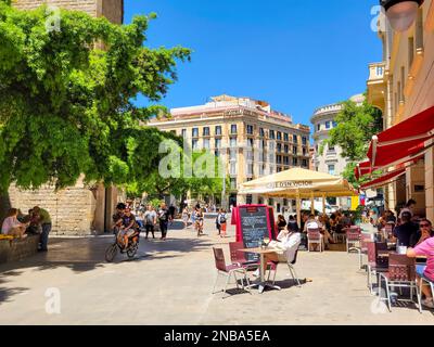 Blick von draußen auf Touristen, die Straßencafés an der Placita de la Seu, der plaza an der Kathedrale von Barcelona genießen. Stockfoto