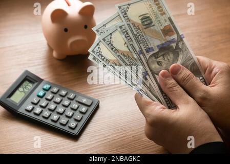 Geschäfts- und Finanzkonzept mit Taschenrechner, Sparschwein und handgehaltenem Geld. Stockfoto