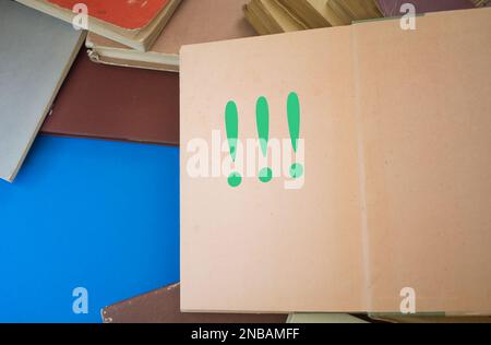 Ausrufezeichen in einem geöffneten Buch mit alten, natürlichen Mustern und altem Papierdesign. Stockfoto