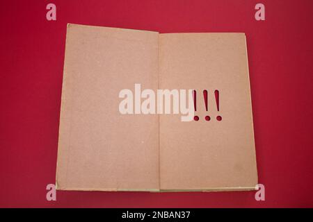 Ausrufezeichen in einem geöffneten Buch mit alten, natürlichen Mustern und altem Papierdesign. Stockfoto