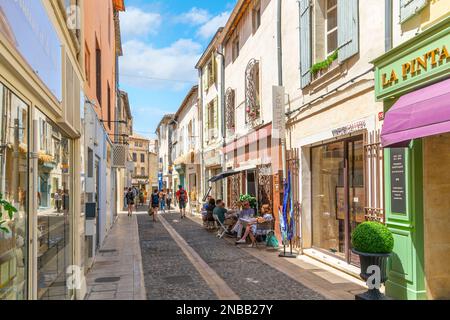 Eine der vielen typischen Straßen und Gassen mit bunten Straßencafés und Geschäften in der historischen Stadt Saint-Remy-de-Provence an einem sonnigen Sommertag. Stockfoto