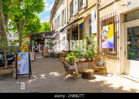 Eine der vielen typischen Straßen und Gassen mit bunten Straßencafés und Geschäften in der historischen Stadt Saint-Remy-de-Provence an einem sonnigen Sommertag. Stockfoto