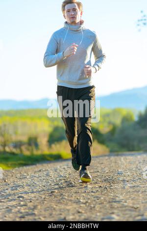 Jogging Mann Joggen in ländlicher Natur an schönen Sommertag. Sport Fitness Modell kaukasischen Ethnizität Training im Freien. Stockfoto