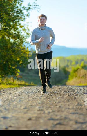 Jogging Mann Joggen in ländlicher Natur an schönen Sommertag. Sport Fitness Modell kaukasischen Ethnizität Training im Freien. Stockfoto