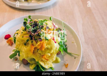Nahaufnahme der köstlichen Eier benedict auf dem Teller, dekoriert mit Mikrogrün Stockfoto