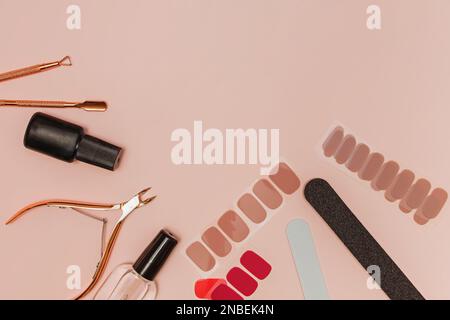 Werkzeuge und Zubehör für Maniküre, Feilen, Nagellack und Nagelstreifen auf pinkfarbenem Hintergrund Stockfoto