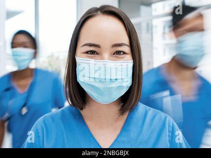 Ohne engagierte Mitarbeiter im Gesundheitswesen werden wir das nicht schaffen. Porträt eines Arztes mit Gesichtsmaske in einem belebten Krankenhaus. Stockfoto