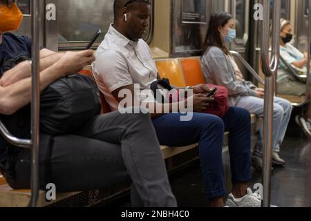 Am Freitag, den 8. Juli 2022, benutzen Passagiere ihre Mobiltelefone in einer U-Bahn in New York City. Stockfoto