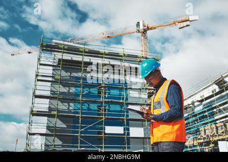 Eine brandneue Entwicklung ist dabei, in Schwung zu kommen. Ein junger Mann, der Papierkram ausfüllt, während er auf einer Baustelle arbeitet. Stockfoto