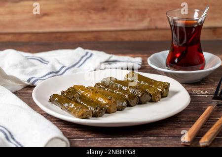 Köstliche Füllung (Yaprak Sarma). Traditionelle türkische Köstlichkeiten. Gefüllte Trauben hinterlässt Reis auf einem Teller auf dem Holzboden Stockfoto