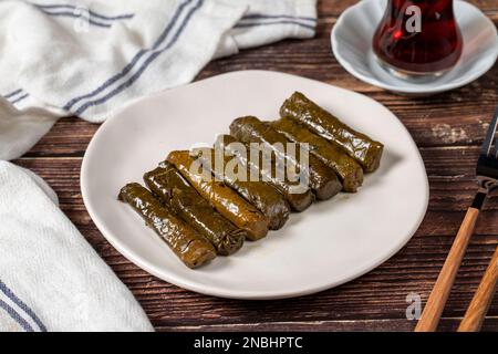 Köstliche Füllung (Yaprak Sarma). Traditionelle türkische Köstlichkeiten. Gefüllte Trauben hinterlässt Reis auf einem Teller auf dem Holzboden. Schließen Stockfoto