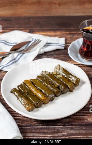 Köstliche Füllung (Yaprak Sarma). Traditionelle türkische Köstlichkeiten. Gefüllte Trauben hinterlässt Reis auf einem Teller auf dem Holzboden. Schließen Stockfoto