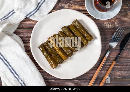 Köstliche Füllung (Yaprak Sarma). Traditionelle türkische Köstlichkeiten. Gefüllte Trauben hinterlässt Reis auf einem Teller auf dem Holzboden. Draufsicht Stockfoto