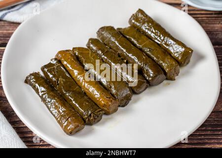 Köstliche Füllung (Yaprak Sarma). Traditionelle türkische Köstlichkeiten. Gefüllte Trauben hinterlässt Reis auf einem Teller auf dem Holzboden. Schließen Stockfoto