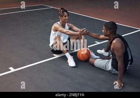 Es ist immer gut, mit dir zu spielen, Alter. Zwei sportliche junge Männer, die sich auf einem Basketballfeld die Hand schütteln. Stockfoto