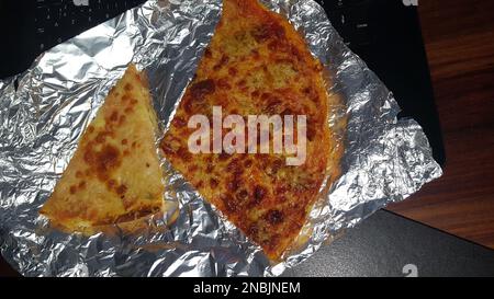 Pizza frisch auf Aluminiumfolie am Computer während der Mittagspause Stockfoto