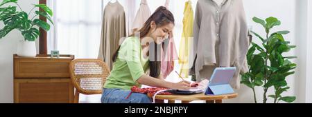 Mode Kleidung Online-Konzept, weibliche Blogger messen Größe des Kleides und Notizen auf Notebook. Stockfoto