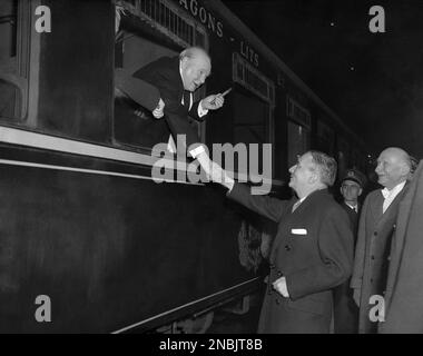 Britain’s Prime Minister Winston Churchill, holding familiar cigar, leans from a train window at Gare du Nord, Paris, France on Dec. 18, 1951, to big goodbye, to French Defense Minister Georges Bidault and Foreign Minister Robert Schuman. Churchill was leaving the French capital after conferences with other West European leaders. (AP Photo)