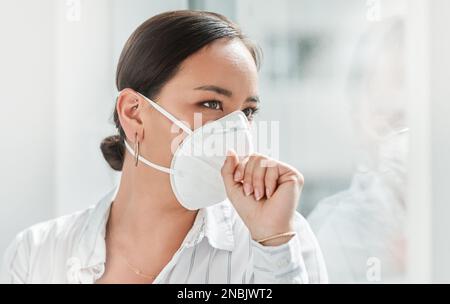 Ein kleines Symptom, das auf etwas großes hinweisen könnte. Eine maskierte junge Geschäftsfrau hustet in einem modernen Büro. Stockfoto