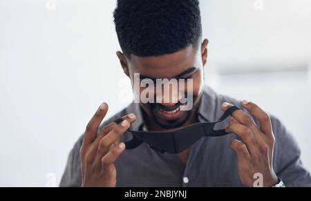 Es wird ein neuer Teil seiner Geschäftsuniform. Ein junger Geschäftsmann, der in einem Büro eine Gesichtsmaske aufsetzt. Stockfoto
