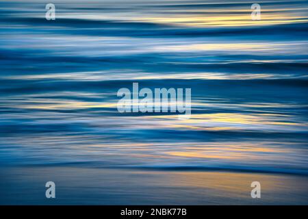 Abstrakter Ozean bei Sonnenuntergang. Das Bild wird durch Schwenken der Kamera verschwommen aufgenommen. Blaue und türkisfarbene Meereswellen. Stockfoto
