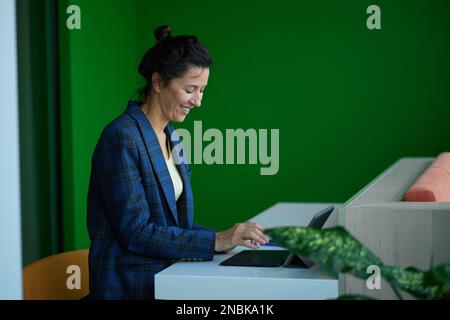 Porträt einer Geschäftsfrau, die im Büro am Laptop sitzt und lächelt. Hochwertiges Foto Stockfoto