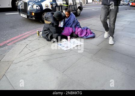 London, England, Großbritannien. Obdachloser Mann und Frau, die auf dem Bürgersteig in der Oxford Street sitzen Stockfoto