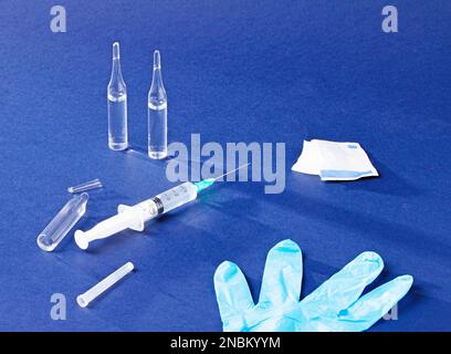 Set für Injektionen - Spritze, Ampullen und ein Alkoholtupfer auf blauem Hintergrund Stockfoto