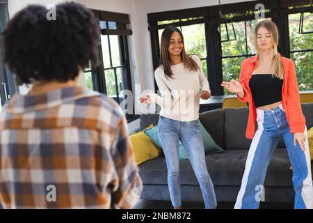 Fröhliche, vielfältige weibliche Teenager-Freunde, die tanzen und einen Video-Blog aufnehmen. Das Konzept „Zeit zu Hause verbringen“. Stockfoto