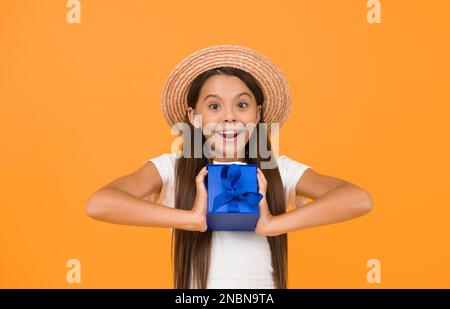 Herzlichen Glückwunsch. Ein überraschtes kleines Mädchen hält die Geschenkbox. Ein schönes Geschenk. Sommerfeiertag. Fröhliche Feiertagsfeier. Netter kleiner Kauf Stockfoto