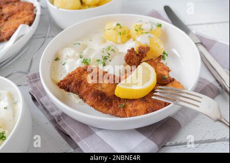 Paniertes Hähnchenschnitzel mit Kohlrabi-Gemüse mit Béchamel-Sauce und gekochten Kartoffeln auf einem Teller. Hausgemacht Stockfoto