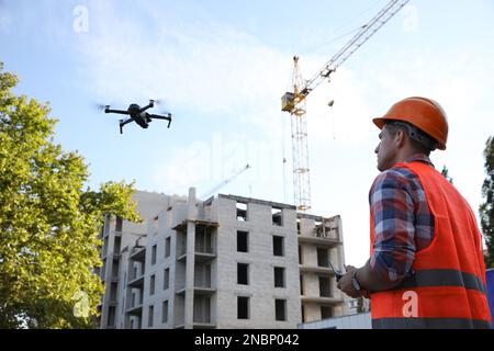 Bauarbeiter, die Drohne mit Fernsteuerung auf der Baustelle bedienen. Luftaufnahmen Stockfoto