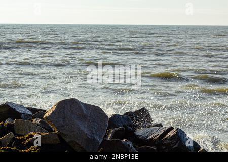 Eine wunderschöne Küste mit einer Welle und großen Steinen, die Wellen brechen auf den Felsen Stockfoto