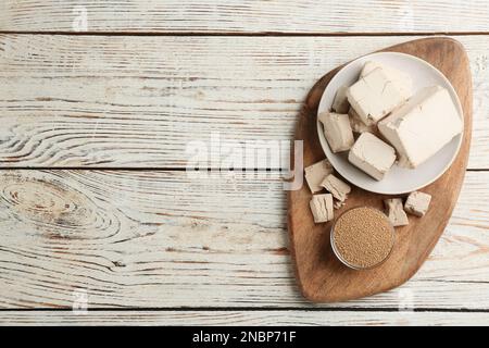 Komprimierte und granulierte Hefe auf weißem Holztisch, Draufsicht. Platz für Text Stockfoto