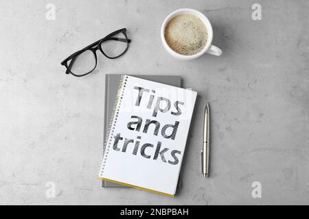 Notizbuch mit Text Tipps und Tricks auf grauem Tisch, flach liegend Stockfoto
