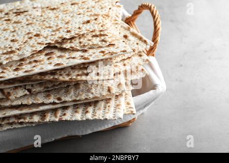 Traditionelle Matzen im Korb auf hellgrauem Tisch, Nahaufnahme Stockfoto