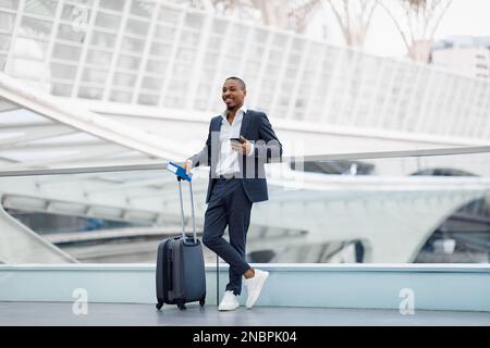 Hübscher Afroamerikanischer Geschäftsmann Mit Koffer Am Flughafen Stockfoto