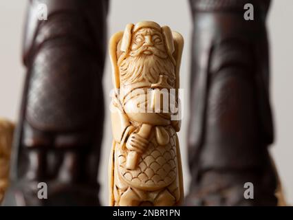 Chinesische orientalische Schachfiguren, mit dem weißen König Kaiser zwischen zwei schwarzen Stücken. Antikes Schachset und Brett Stockfoto