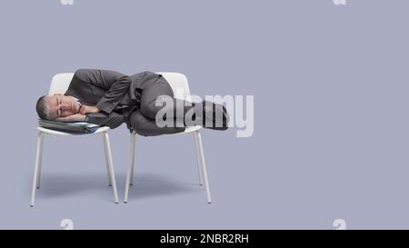 Erschöpfter Geschäftsmann legt sich auf Stühle und schläft Stockfoto