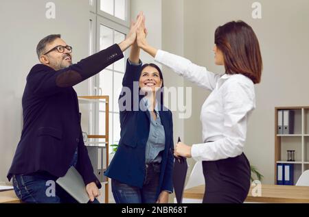 Glückliches erfolgreiches Business-Team gibt High Fives und jubelt seinen Erfolg an Stockfoto