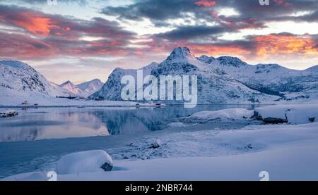 Erstaunlicher Sonnenaufgang im Winter über dem Polarkreis. Gefrorener Boosen-Fjord auf Flakstadoya Island. Majestätische Morgenszene der Lofoten-Inseln mit Hustinden Moun Stockfoto