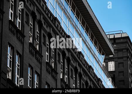 Stilvolles Gebäude aus altem Ziegelstein mit modernen, energiesparenden Metall-Kunststoff-Fenstern. Urbaner Stil, Restaurierung alter Gebäude Stockfoto