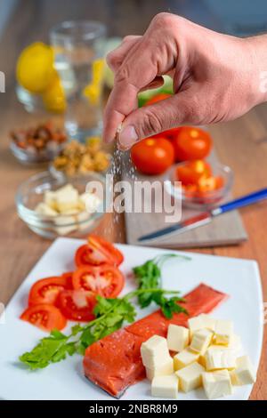 Männliche Hand fügt Salz auf Lachsfilet hinzu. Gesundes Essen. Keto-Diät. SDOF Stockfoto