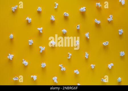 Popcorn-Muster auf gelbem Hintergrund. Draufsicht. Kontrastkonzept. Popcorn auf farbigem Hintergrund Stockfoto