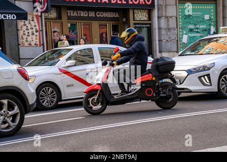 Ein Elektromotorrad der Firma acciona wird in einer Minute gemietet, die über die gran Via Straße in madrid zwischen mehreren Autos und Taxis fährt. Stockfoto