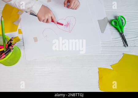 Das Kind zeichnete ein Herz auf weißem Papier. Kreativität des Kindes. Zeichnungsunterricht im Kindergarten. Liebeserklärung für mom. Muttertag Stockfoto