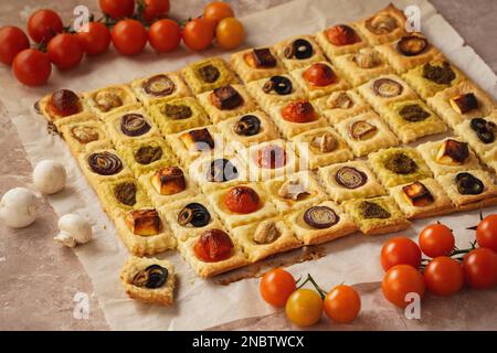 Blätterteiggebäck mit Kirschtomaten, Pilzen, Oliven, Fetakäse und Zwiebeln. Stockfoto