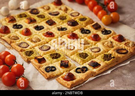 Blätterteiggebäck mit Kirschtomaten, Pilzen, Oliven, Fetakäse und Zwiebeln. Stockfoto